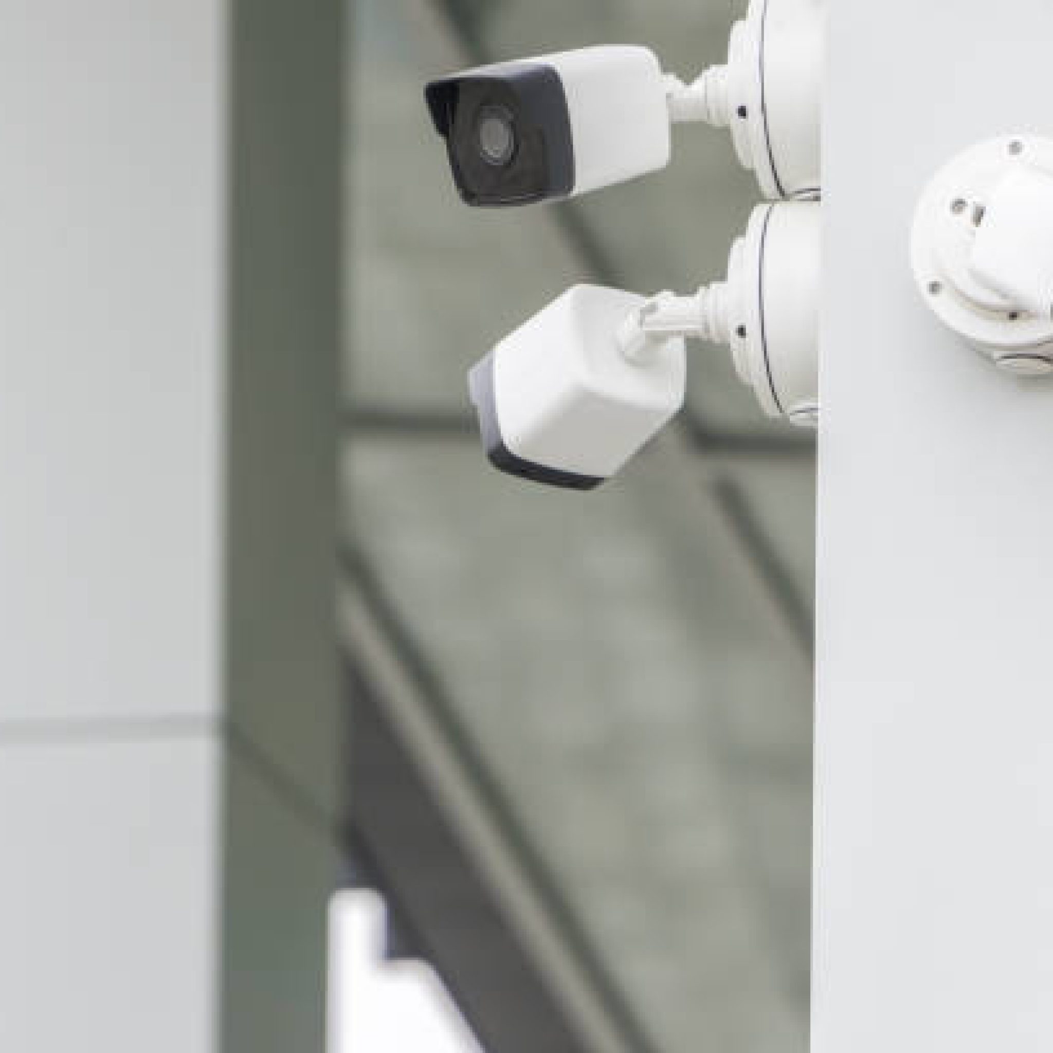 Outdoor CCTV security cameras installed on the modern white building wall in the city. Concept of surveillance and monitoring.